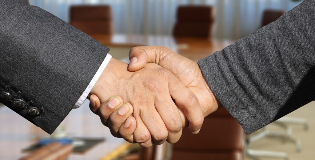 Handshake zwischen interner HR-Managerin und externem Recruitment-Spezialisten im Büro, dies zeigt erfolgreiche Zusammenarbeit durch Recruitment as a Service (Raas)